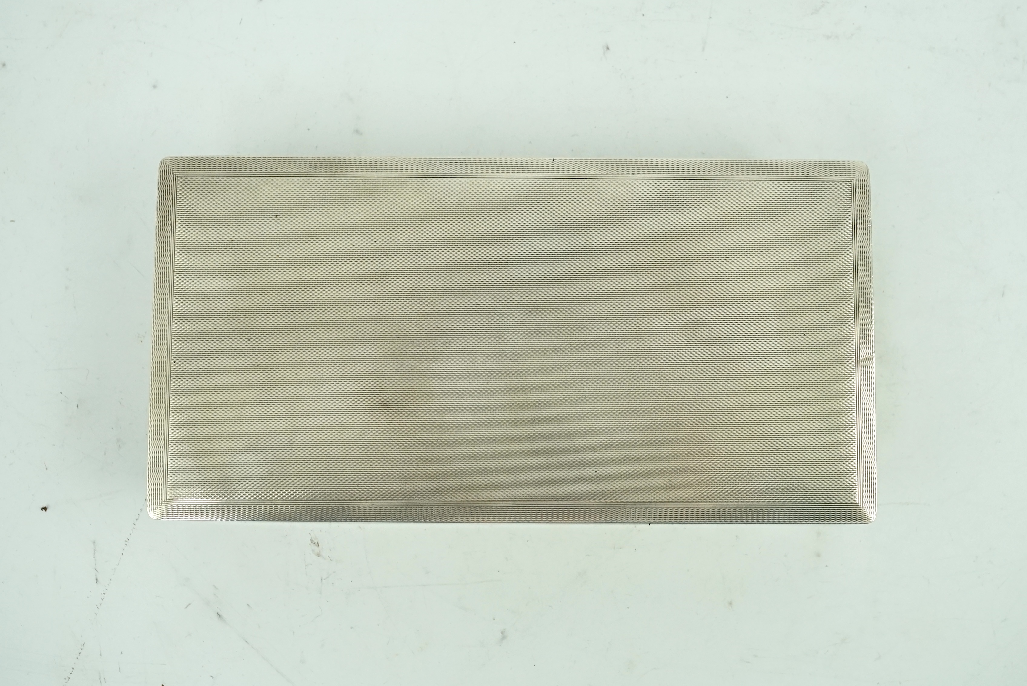 An Elizabeth II engine turned silver cigarette box by Alfred Dunhill